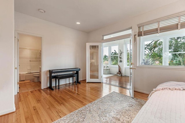 bedroom with connected bathroom, french doors, and light wood-type flooring