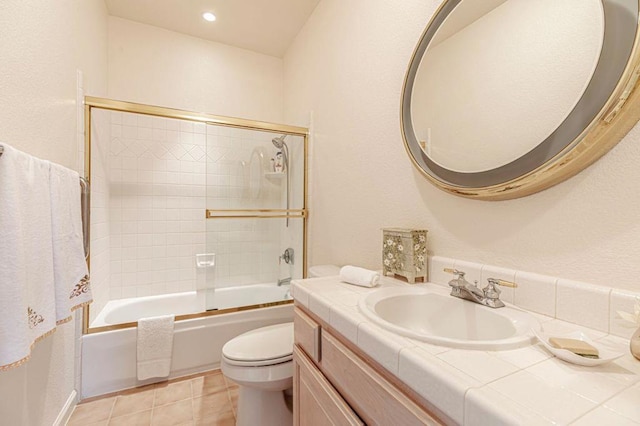 full bathroom featuring tile patterned flooring, vanity, bath / shower combo with glass door, and toilet