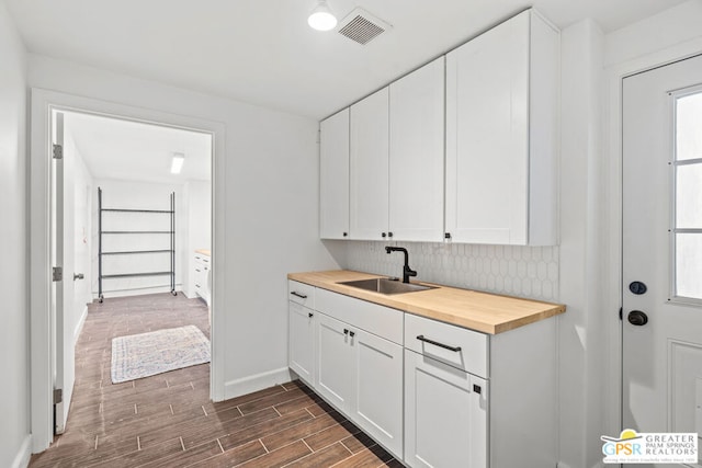 kitchen with sink, white cabinets, and butcher block countertops