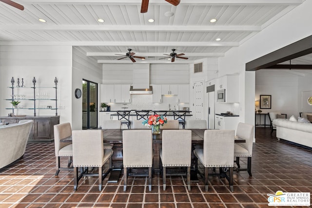 dining area with ceiling fan, beam ceiling, and dark tile patterned flooring