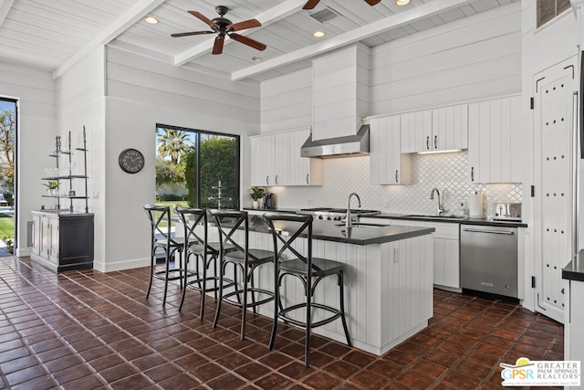 kitchen featuring stainless steel appliances, an island with sink, white cabinets, and a kitchen bar