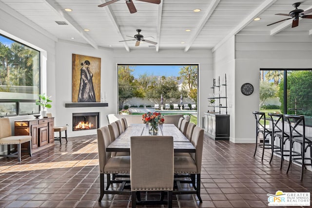 dining room with beamed ceiling, dark tile patterned floors, and a wealth of natural light