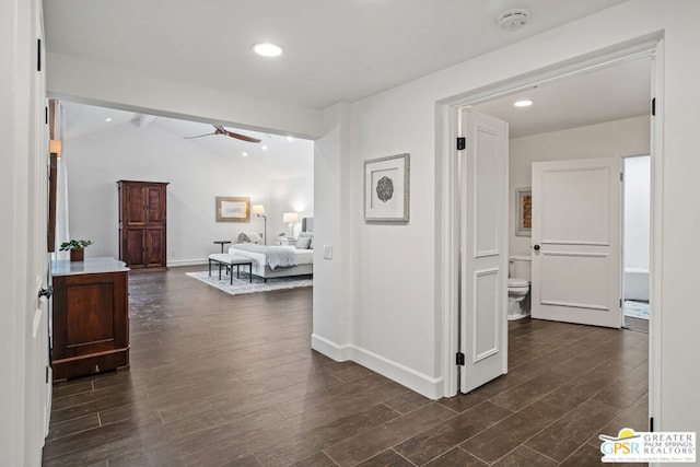 corridor with dark hardwood / wood-style flooring and lofted ceiling with beams