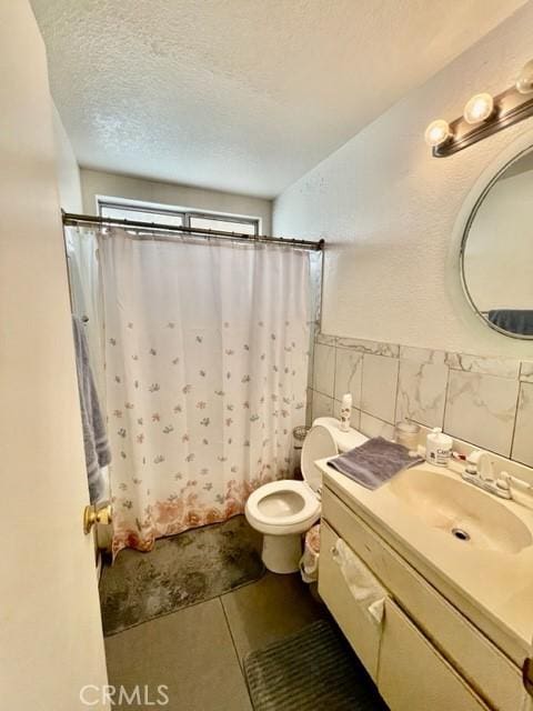 bathroom with toilet, a textured ceiling, tile walls, vanity, and tile patterned flooring