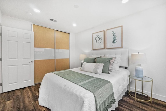 bedroom with dark wood-type flooring and a closet