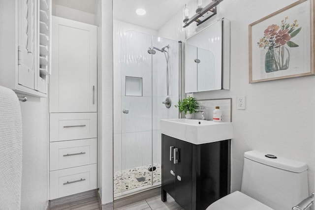 bathroom featuring vanity, a shower with shower door, and toilet