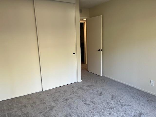 unfurnished bedroom featuring light colored carpet and a closet