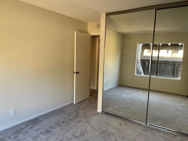 unfurnished bedroom with carpet floors, a closet, and a textured ceiling