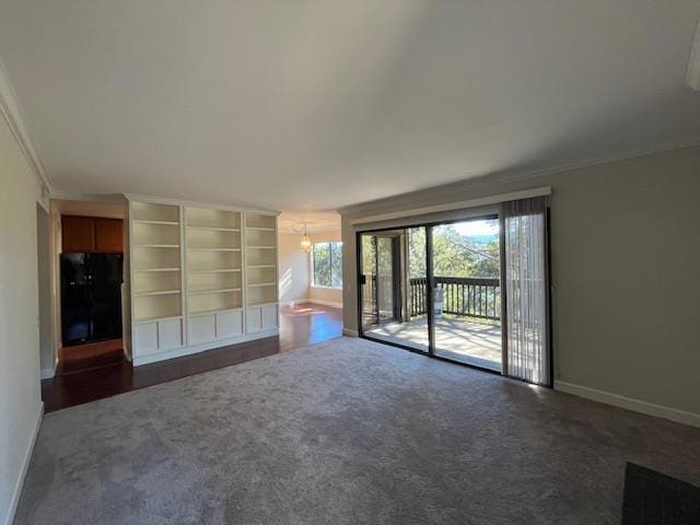 unfurnished living room featuring dark colored carpet, crown molding, and a notable chandelier