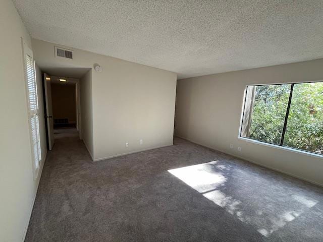 spare room featuring a textured ceiling and dark carpet