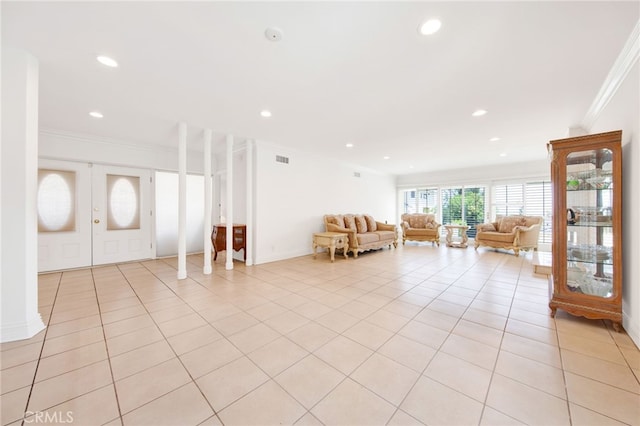 unfurnished living room with light tile patterned floors, ornamental molding, and french doors