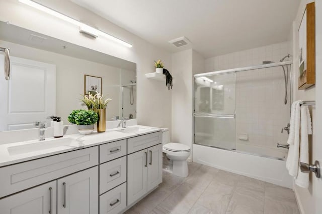 full bathroom with enclosed tub / shower combo, vanity, and toilet