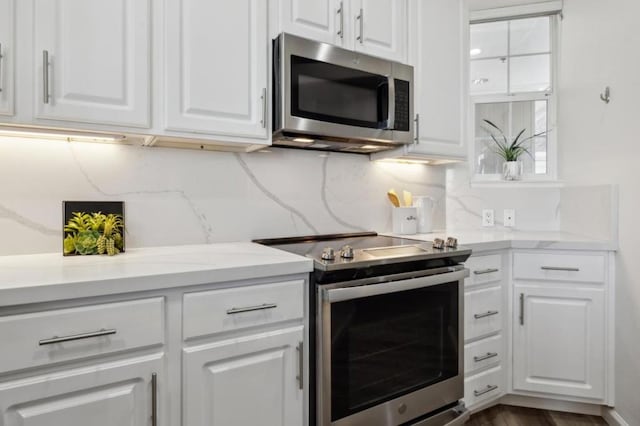 kitchen with white cabinetry, decorative backsplash, light stone countertops, and appliances with stainless steel finishes