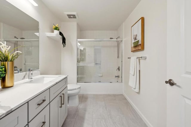 full bathroom with enclosed tub / shower combo, vanity, and toilet