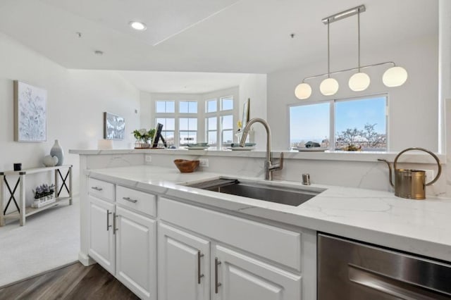 kitchen with white cabinetry, sink, hanging light fixtures, stainless steel dishwasher, and light stone countertops