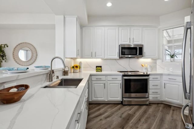 kitchen featuring white cabinetry, sink, stainless steel appliances, light stone countertops, and dark wood-type flooring