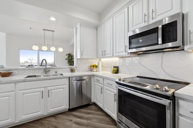 kitchen featuring pendant lighting, sink, white cabinetry, stainless steel appliances, and tasteful backsplash