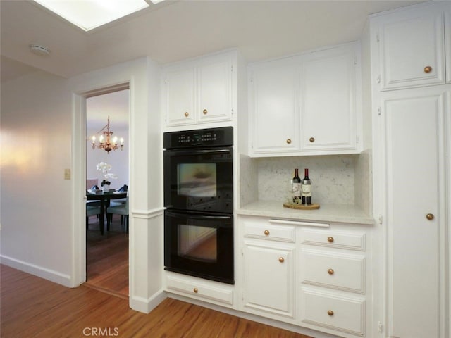 kitchen featuring backsplash, light hardwood / wood-style floors, black double oven, and white cabinets