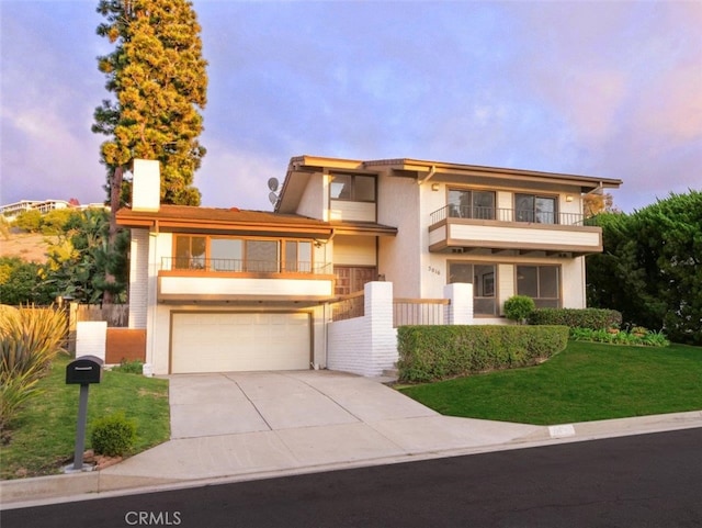 view of front of property with a garage, a balcony, and a yard