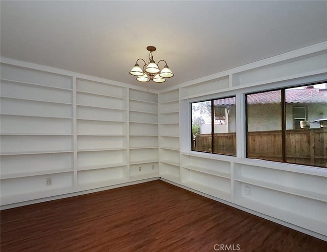 unfurnished room with dark wood-type flooring and a notable chandelier