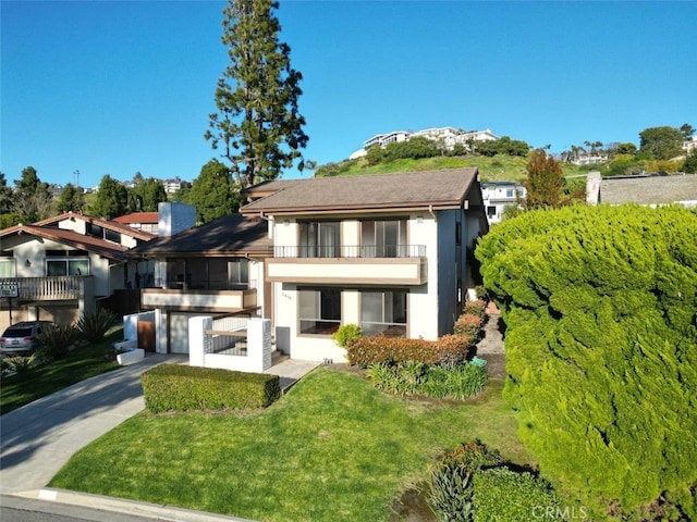 view of front facade with a garage, a front lawn, and a balcony