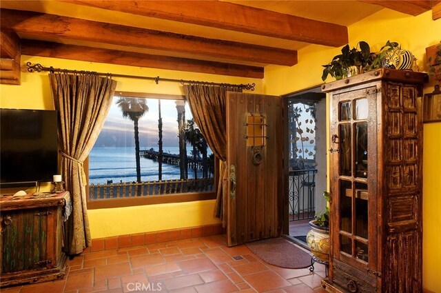 doorway with beamed ceiling and a water view