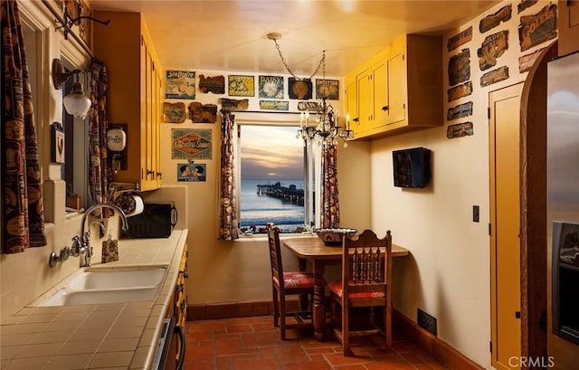 kitchen featuring tile countertops, a chandelier, and sink