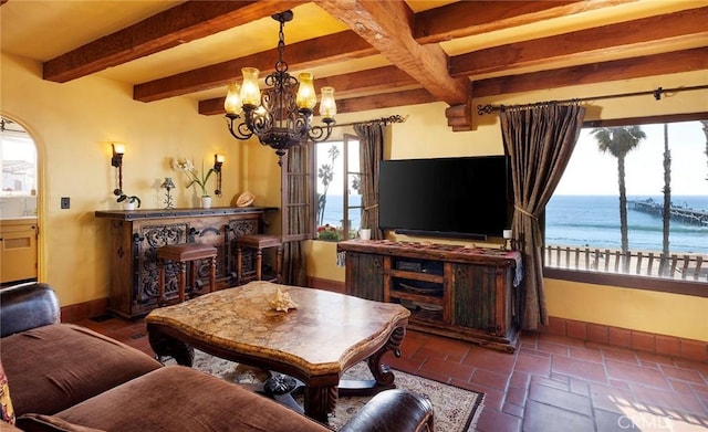 living room with beam ceiling, a notable chandelier, and baseboards