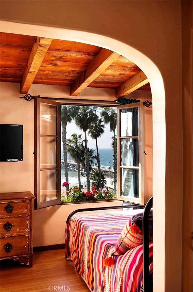 bedroom with hardwood / wood-style floors, beam ceiling, wooden ceiling, and a water view