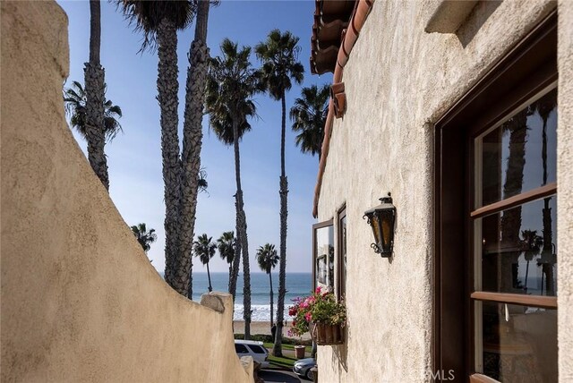 view of property exterior featuring a water view and a view of the beach