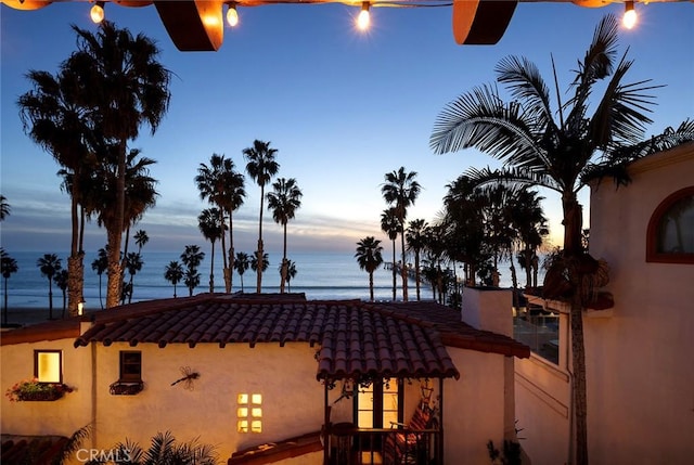 view of property exterior featuring a water view, a tile roof, and stucco siding