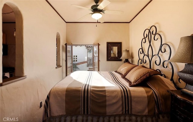 bedroom featuring arched walkways, crown molding, and ceiling fan