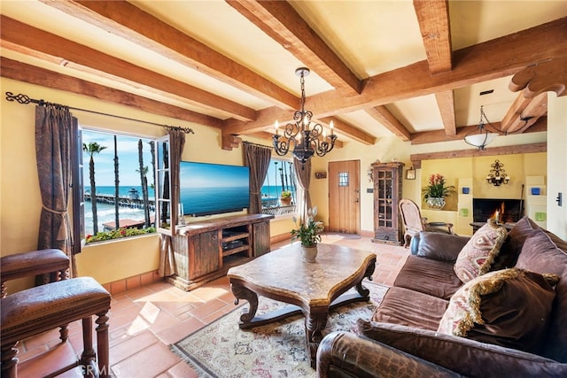 living room with a warm lit fireplace, baseboards, a chandelier, and beam ceiling