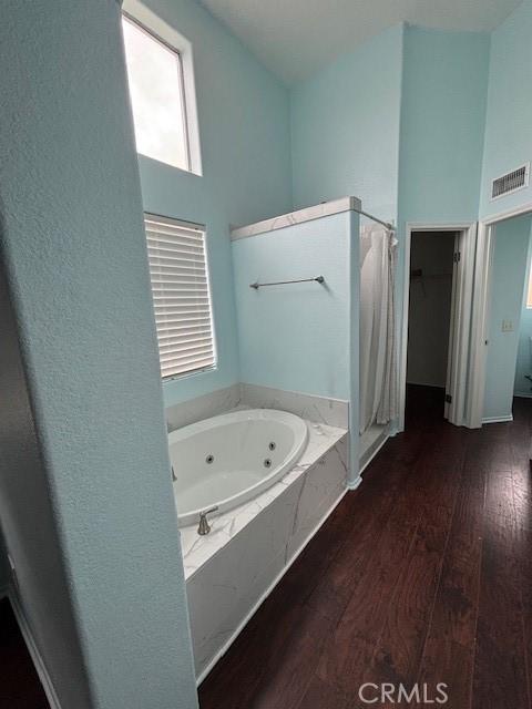 bathroom featuring wood-type flooring, a high ceiling, and a washtub