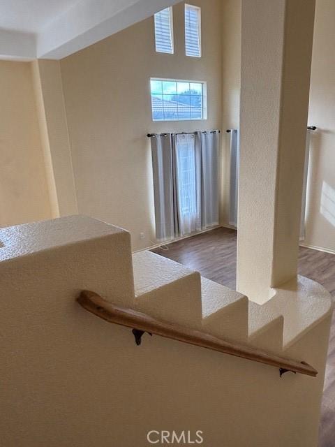 stairway with wood-type flooring and a towering ceiling