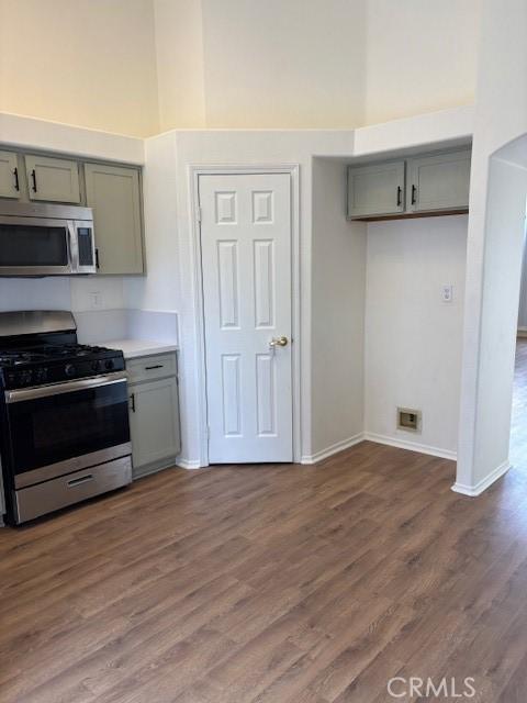 kitchen with stainless steel appliances, a towering ceiling, and dark wood-type flooring