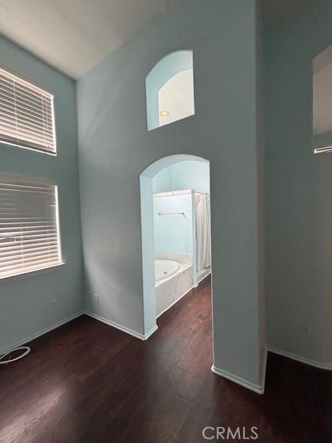 spare room with dark hardwood / wood-style floors and a towering ceiling