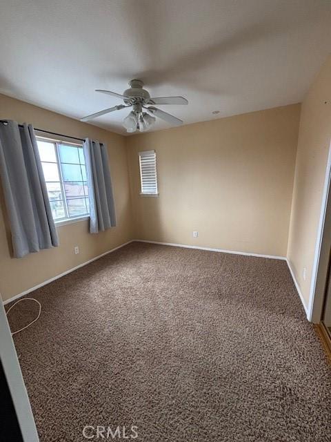 spare room featuring ceiling fan and carpet floors