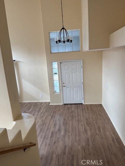 foyer featuring wood-type flooring, a chandelier, and a high ceiling