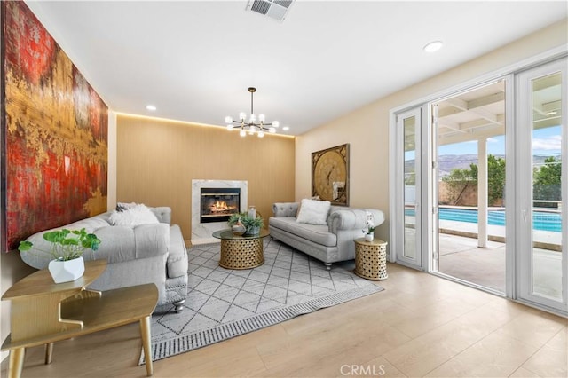 living room featuring a high end fireplace, a chandelier, light hardwood / wood-style flooring, and wood walls