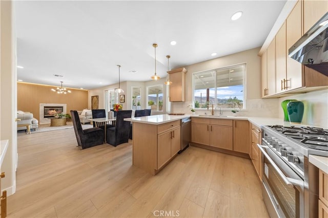 kitchen featuring pendant lighting, kitchen peninsula, stainless steel appliances, light brown cabinets, and light hardwood / wood-style flooring