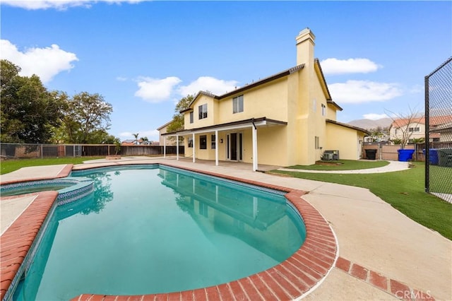 view of swimming pool featuring an in ground hot tub, central AC, a patio, and a lawn