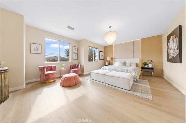 bedroom with a notable chandelier and light wood-type flooring