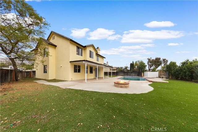 rear view of house with a fenced in pool, a patio area, a lawn, and an outdoor fire pit