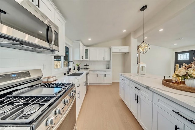 kitchen with light stone counters, light hardwood / wood-style flooring, pendant lighting, stainless steel appliances, and white cabinets