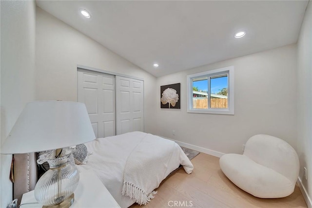 bedroom featuring wood-type flooring, vaulted ceiling, and a closet