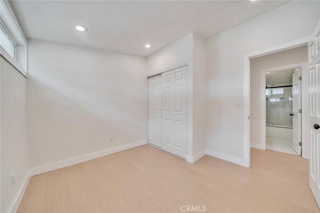 unfurnished bedroom with multiple windows, light hardwood / wood-style floors, and a closet