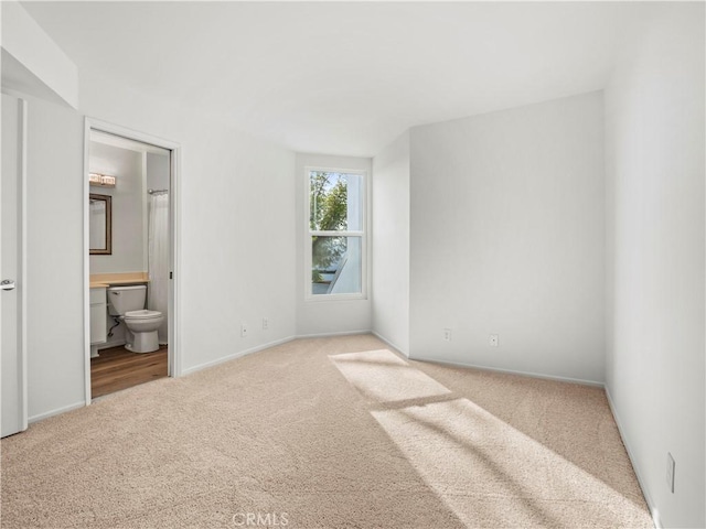 unfurnished bedroom featuring connected bathroom and light colored carpet