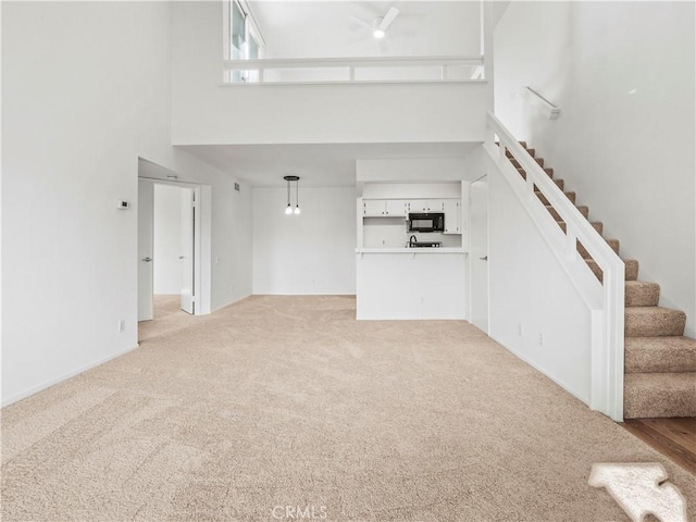 unfurnished living room with light colored carpet and a high ceiling