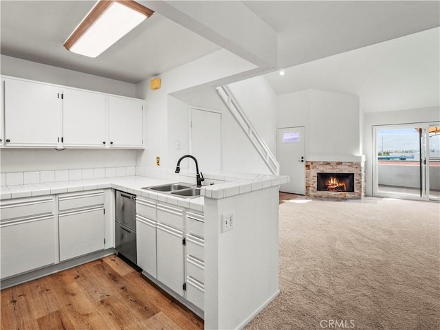 kitchen featuring tile countertops, sink, white cabinets, light colored carpet, and kitchen peninsula